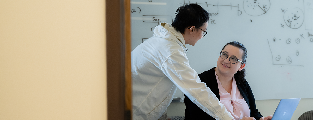 Assistant Professor Marinka Zitnik (seated) discusses research with a member of her lab