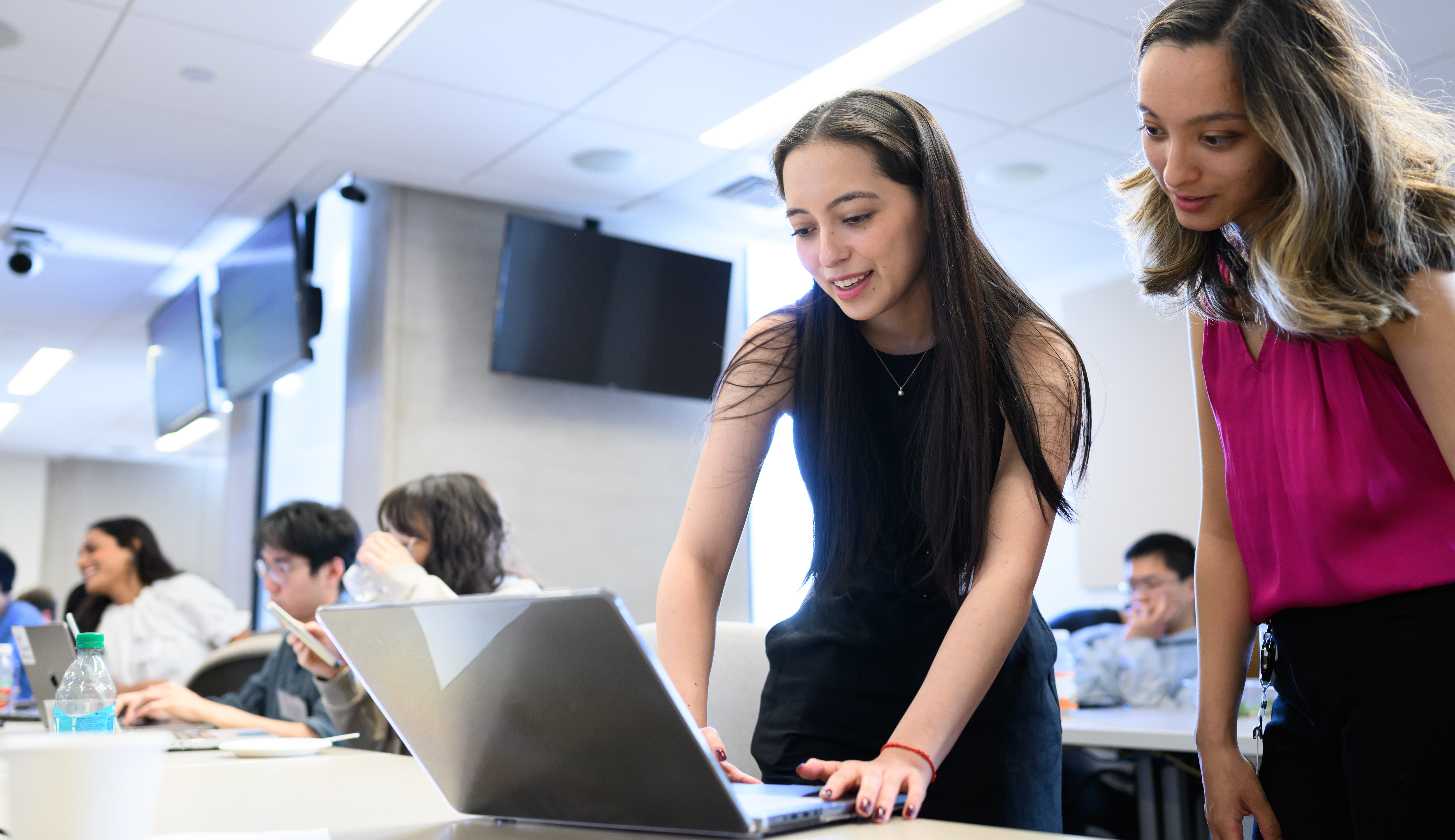 Two students working at laptop