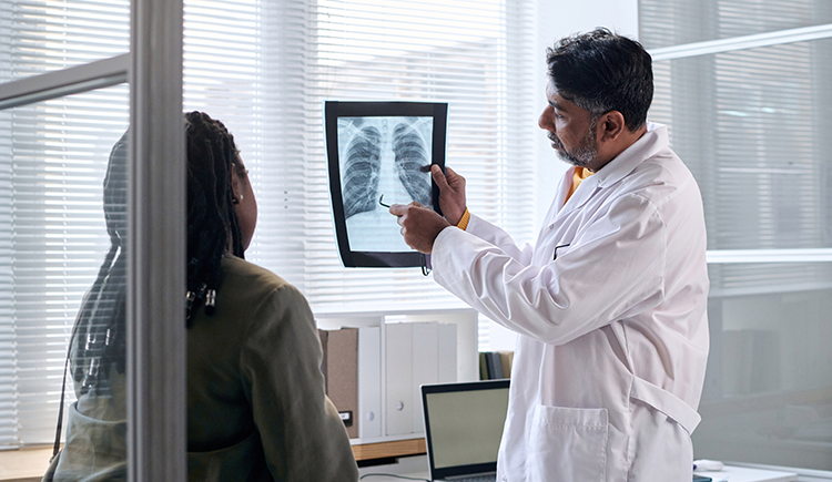 Patient reviews chest x-ray with doctor. -- health equity coverage from STAT